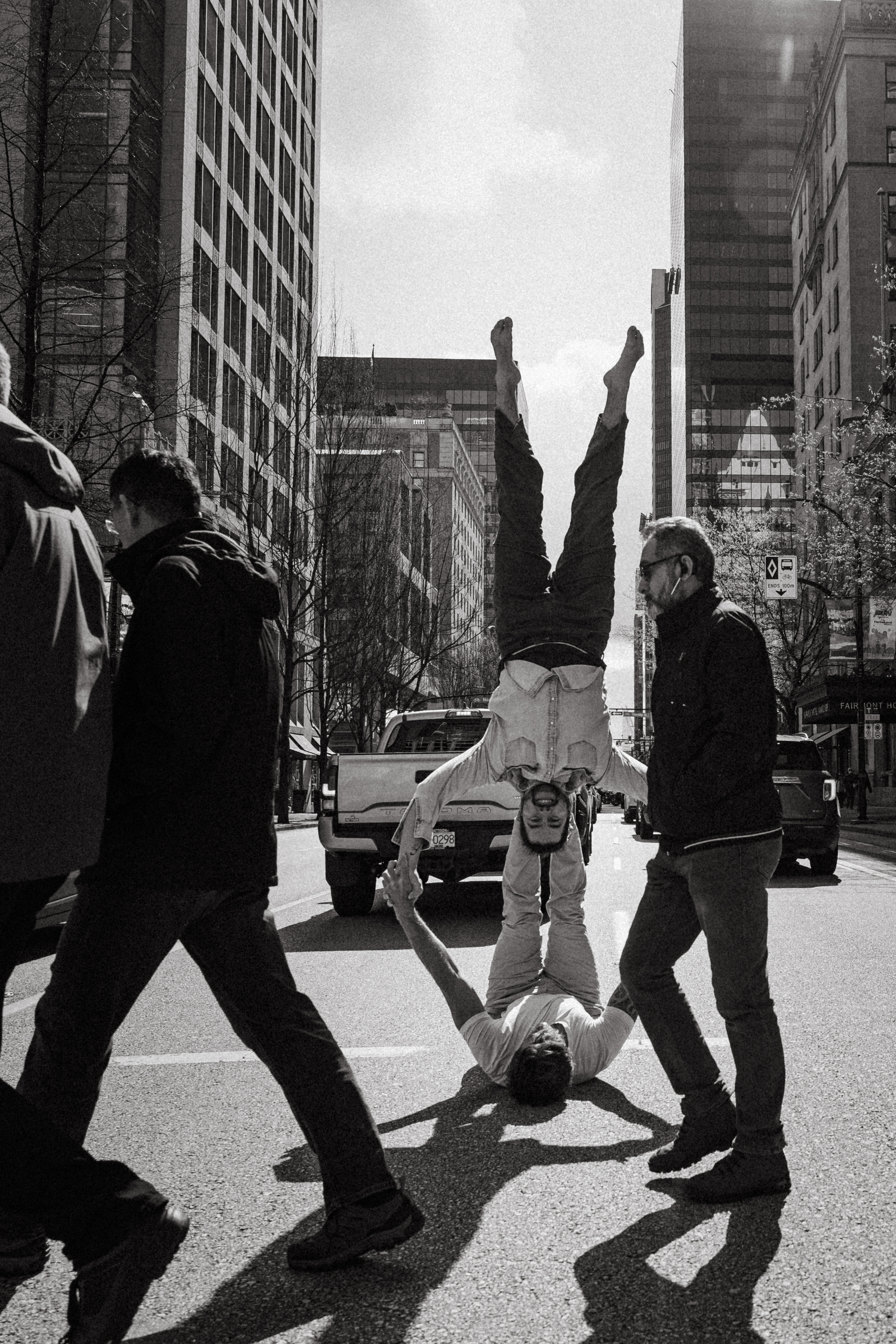 Black-and-white documentary photograph of partner acrobatics in a city street